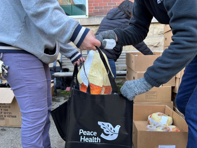 Volunteer puts frozen turkey in bag to distribute to local families as part of Thanksgiving Baskets project.